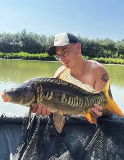 Ragazzo con una carpa a specchi pescata al Lago La Fenice