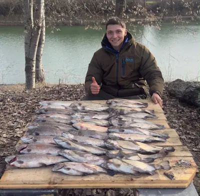 Pescatore con un tavolo pieno di trote pescate al Lago La Fenice